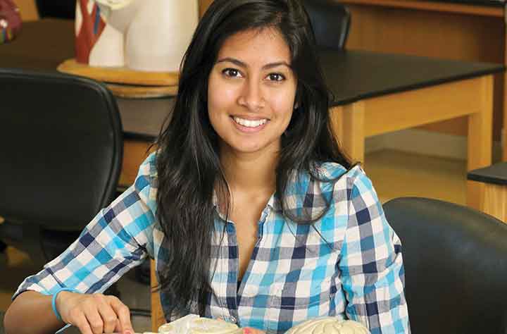 alumnae ADITI DEY ’13 sits at desk with book open