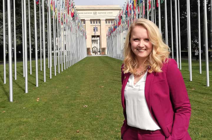 Charline stands in front of a line of international flags.