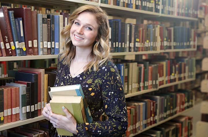 Amber Davis holding books in Willet Library.