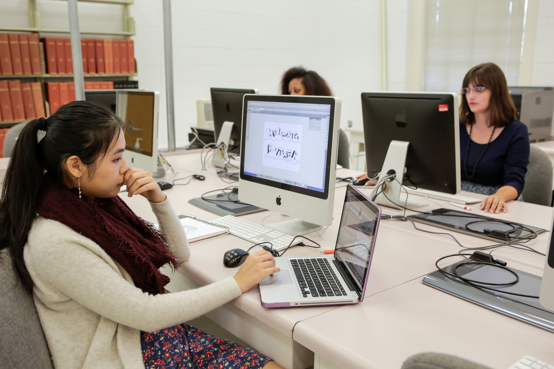 Students working in a computer lab on graphic design artwork. 
