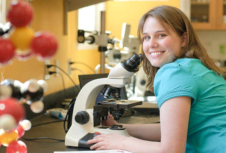 Biology student sitting with microscope