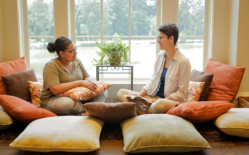 Two students sitting on the floor talking