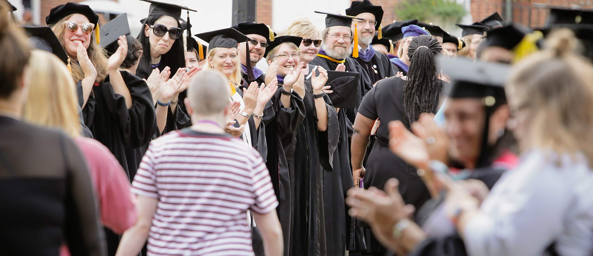 Students and President Vivia Fowler clap as new class walks by.