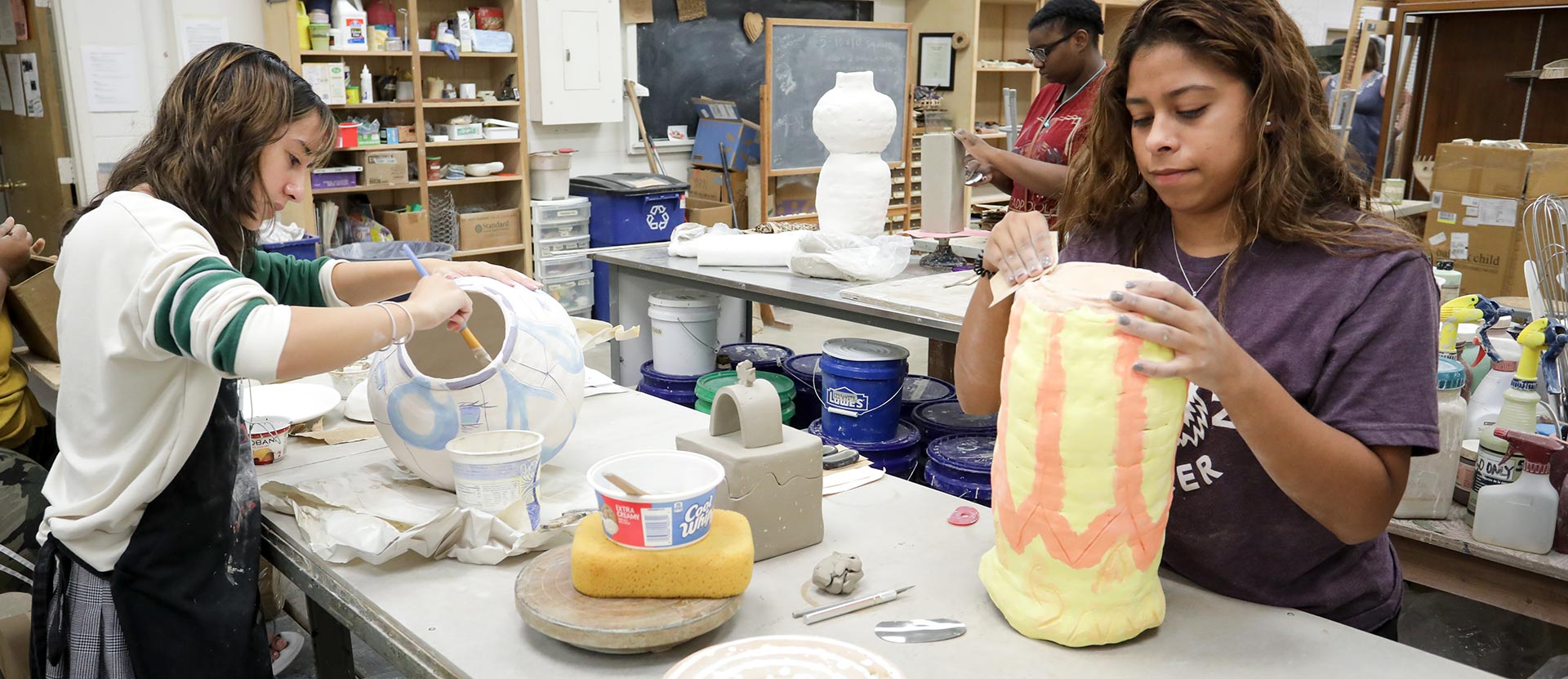 Three art students work on their pottery.