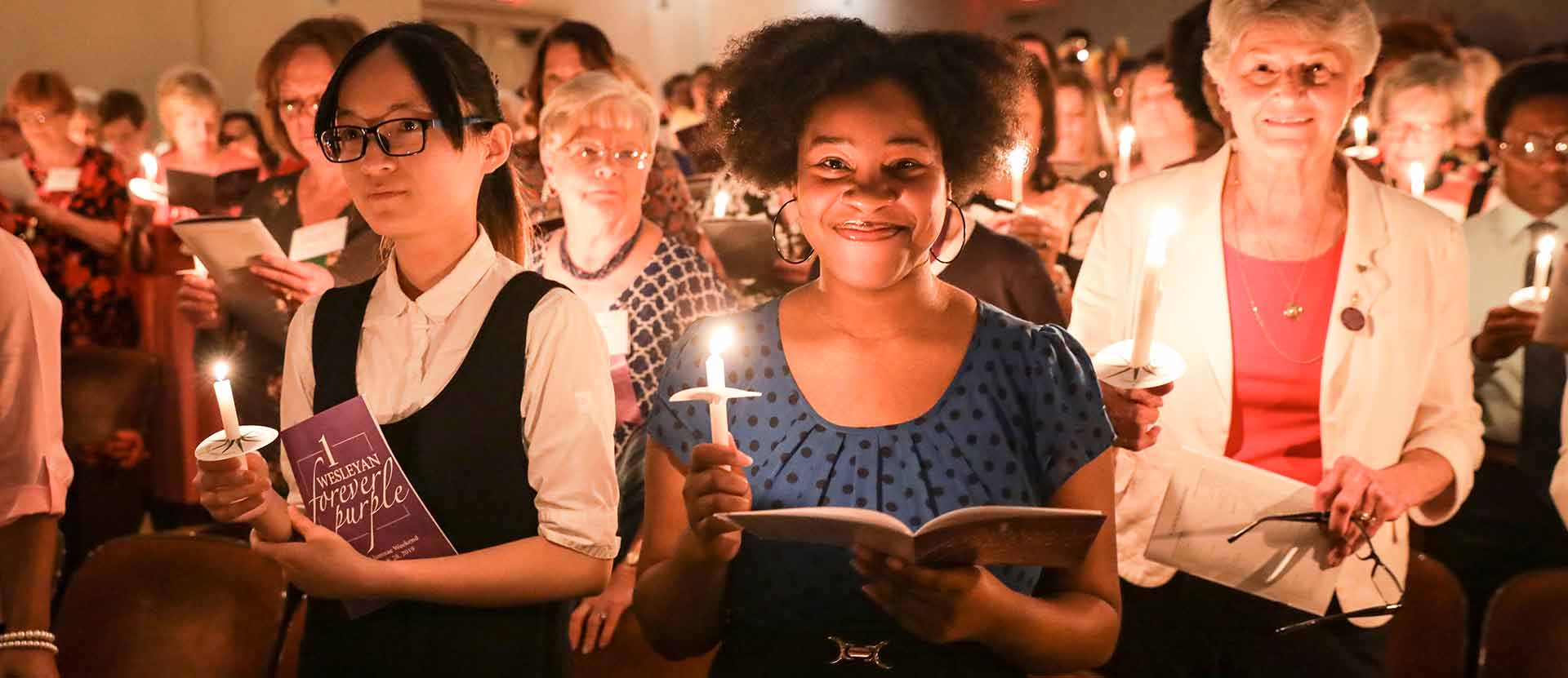 Student holds candle with other alumnae.