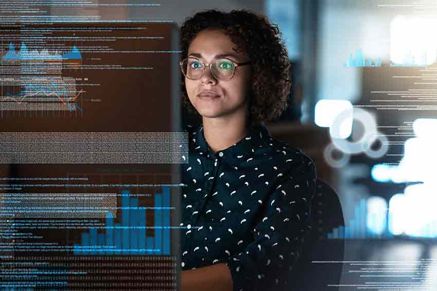 Student looks at computer monitor with data in the background.