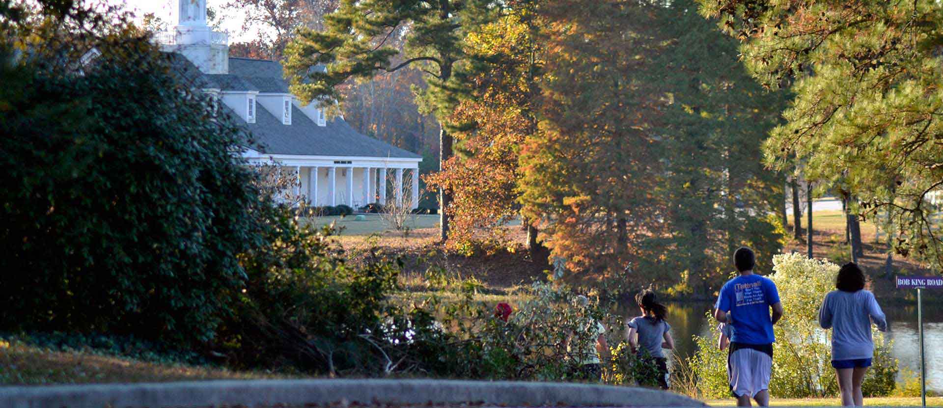 Students and staff run with the president with Mathews Athletic Center in the background