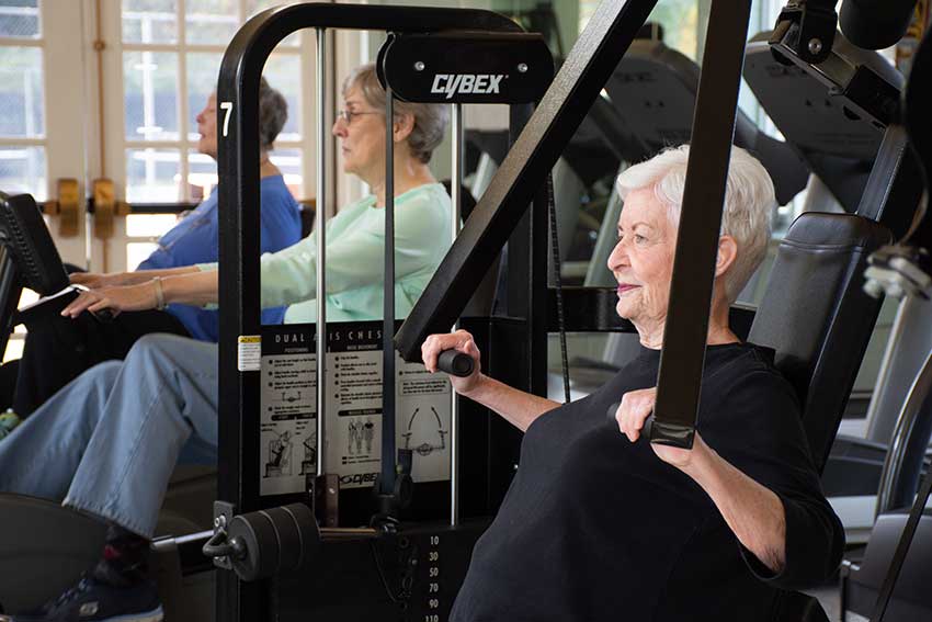 Three women lifting weights in the MAC weight room.