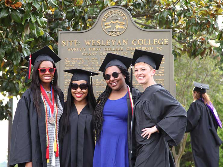 Students stand in front of marker at ceremony
