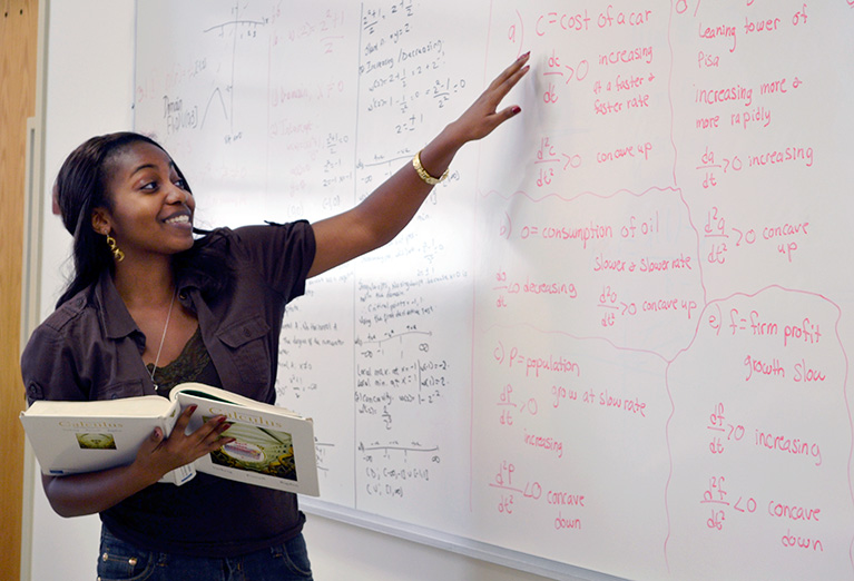 Mathematics students explains formula to class on the whiteboard
