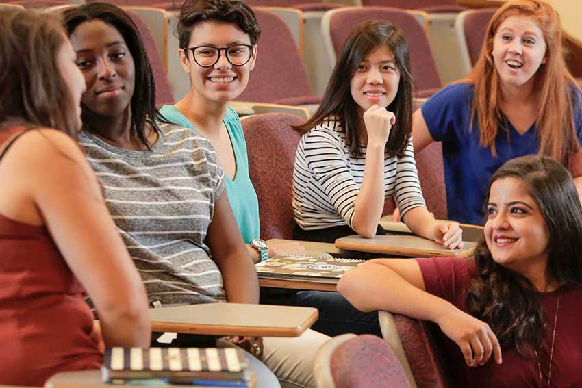 Students sit and talk with smiles.