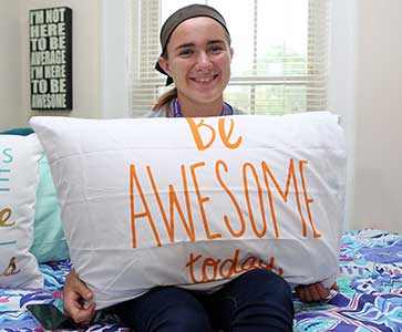 Wesleyan College student in her dorm is holding a pillow with 
