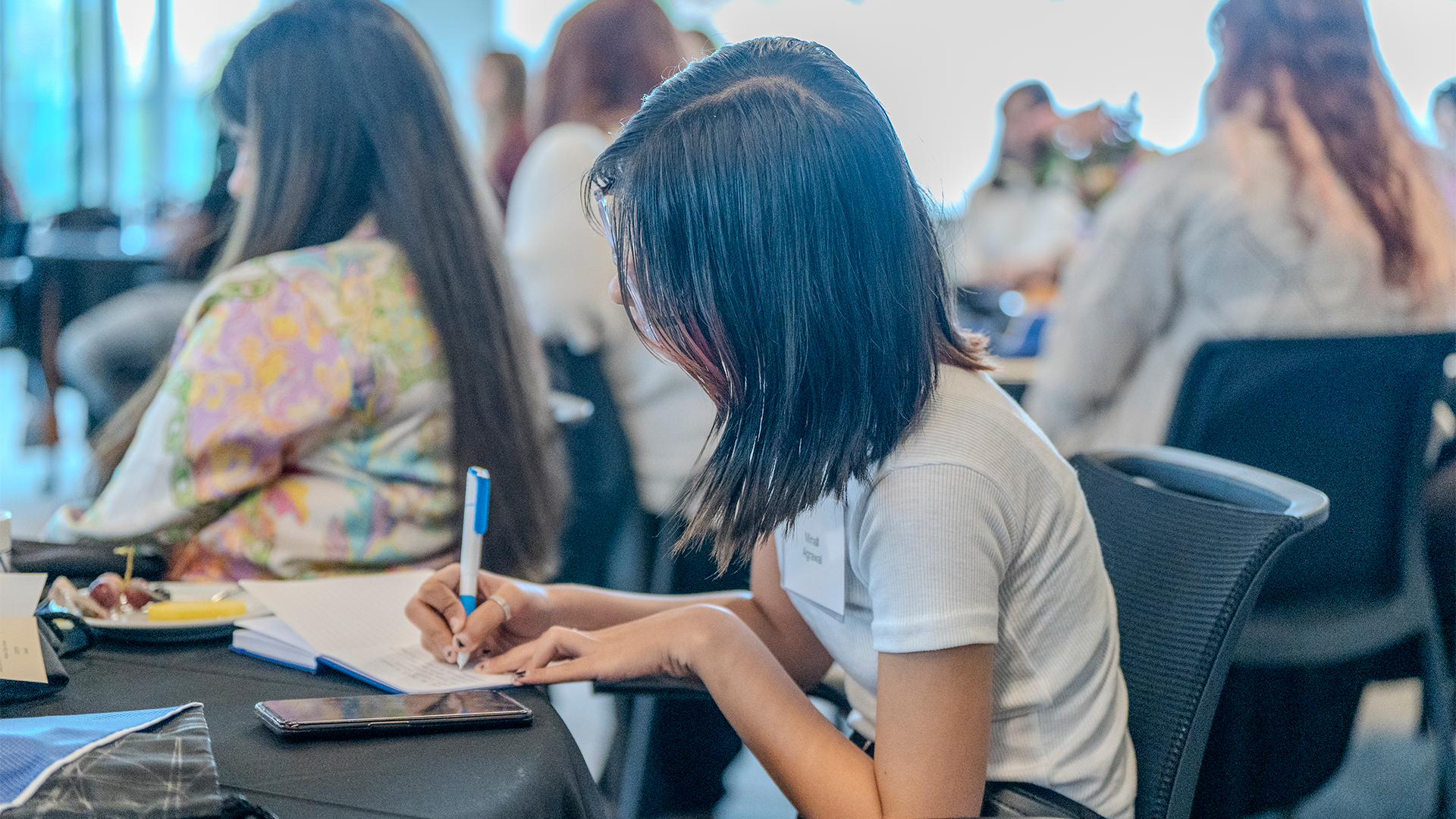 Student at a table, taking notes in notebook
